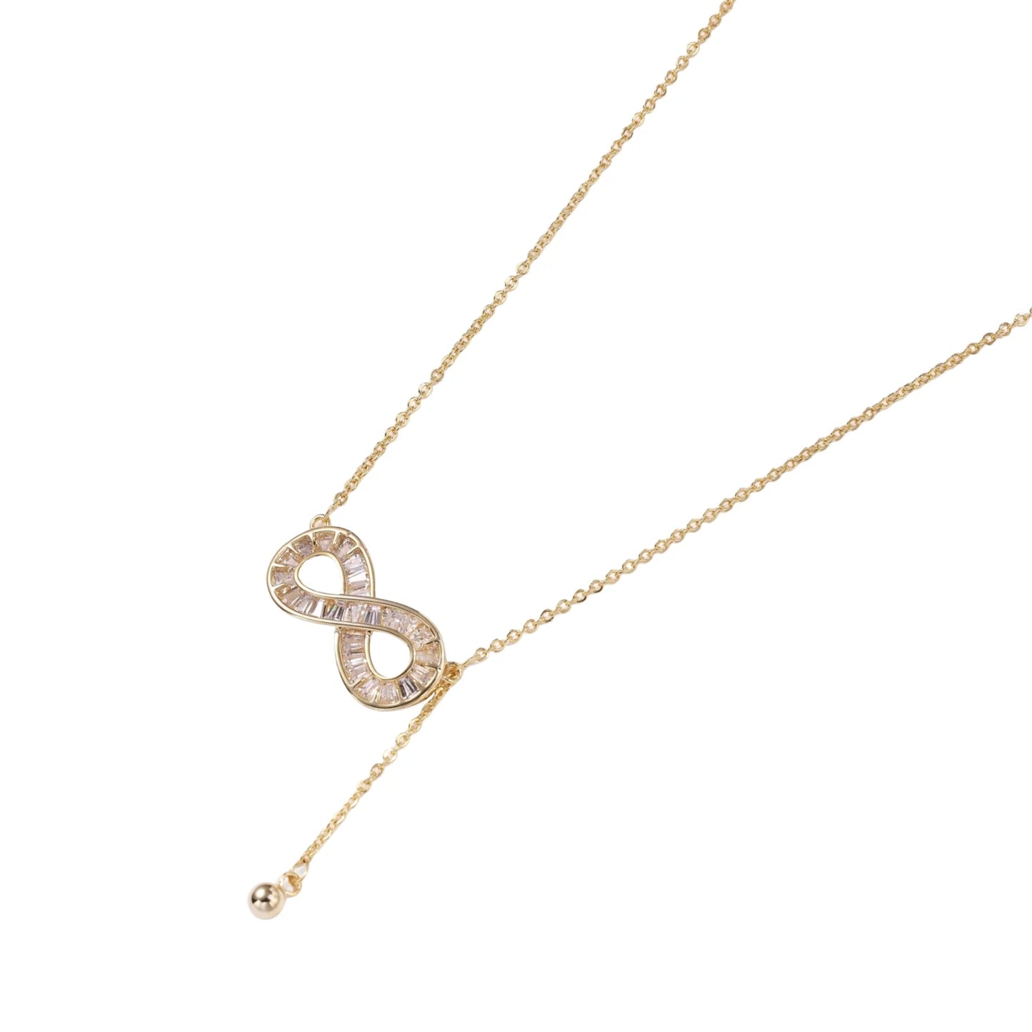 Gold infinity pendant with baguette crystals on adjustable chain against cream background.