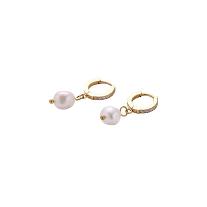 Gold huggie hoop earrings with pavé crystals and white freshwater pearl drops on cream background