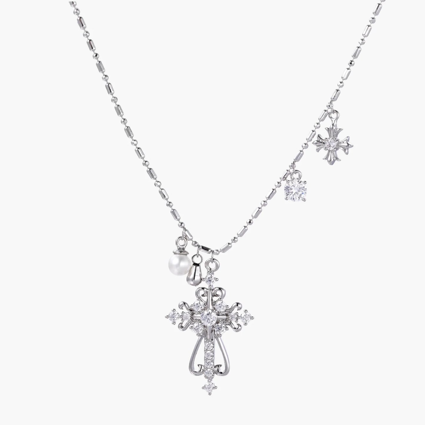 Ornate white gold-plated cross pendant with zirconia stones and pearl accents on adjustable silver chain against cream background