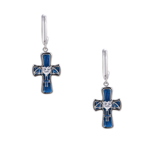 Silver huggie earrings with blue enamel cross charms featuring bat wings and heart-shaped crystal center