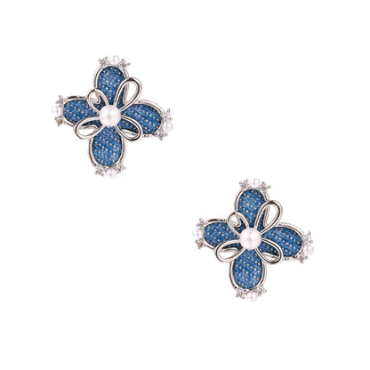 Blue denim fabric flower studs with white gold plated petals, pearl center, and zirconia accents on white background