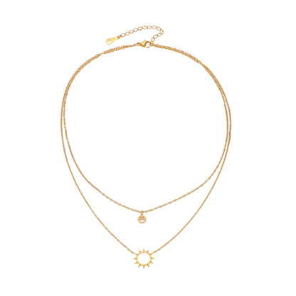 Gold layered necklace set with sunburst and smiley face pendants on delicate chains against white background.