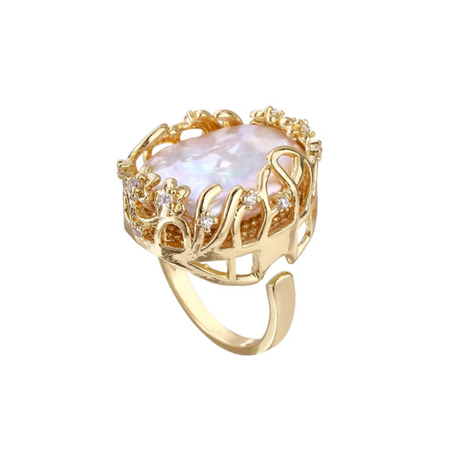 Gold filigree crown ring cradling an iridescent baroque freshwater pearl with crystal accents on white background