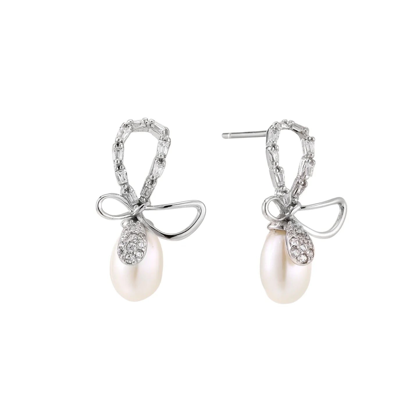 Silver bow-shaped stud earrings with baguette crystals and dangling white freshwater pearls on cream background