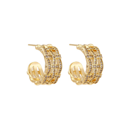 Gold-plated geometric hoop earrings with basket-weave lattice design and pavé crystal accents on cream background