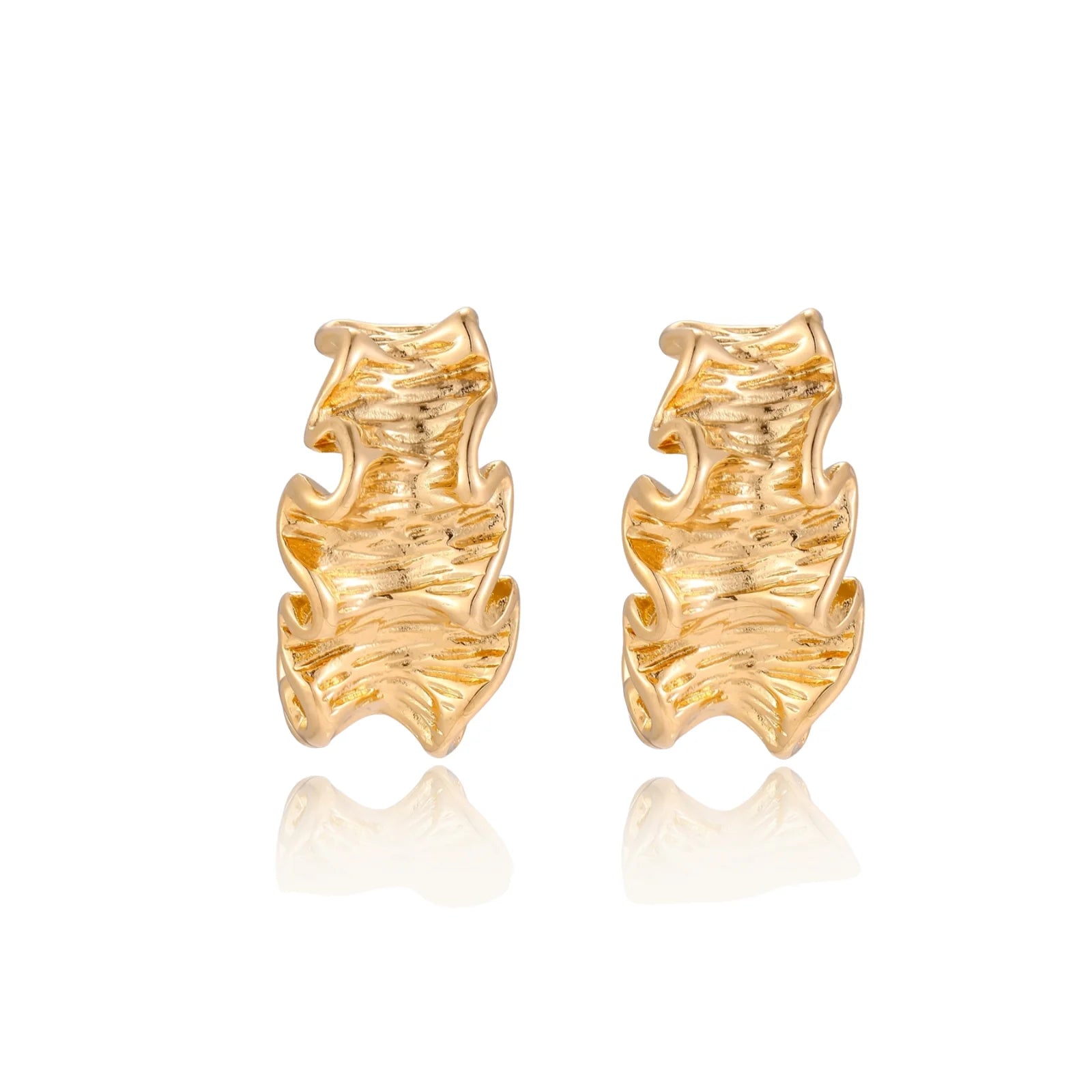 Pair of gold huggie hoops with sculpted wave texture and dimensional ripples on neutral background.